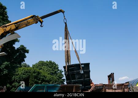 Dnepropetrovsk, Ukraine - 05.28.2021: Müllcontainer mit einem Kran in einen LKW laden. Slinger funktioniert. Stockfoto