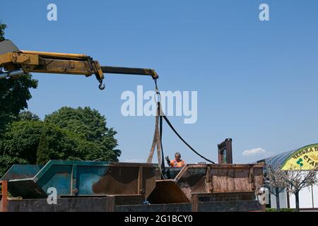 Dnepropetrovsk, Ukraine - 05.28.2021: Müllcontainer mit einem Kran in einen LKW laden. Slinger funktioniert. Stockfoto