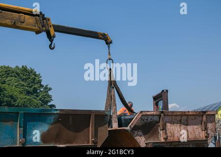 Dnepropetrovsk, Ukraine - 05.28.2021: Müllcontainer mit einem Kran in einen LKW laden. Slinger funktioniert. Stockfoto