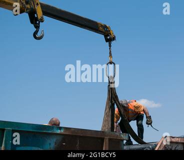 Dnepropetrovsk, Ukraine - 05.28.2021: Müllcontainer mit einem Kran in einen LKW laden. Slinger funktioniert. Stockfoto