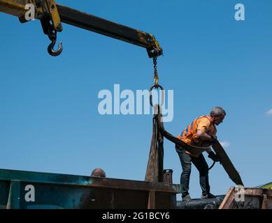 Dnepropetrovsk, Ukraine - 05.28.2021: Müllcontainer mit einem Kran in einen LKW laden. Slinger funktioniert. Stockfoto