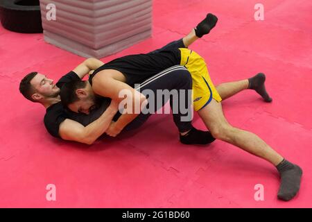 Weißrussland, Minsk - 07. März 2020: Zwei junge sportliche Jungs kämpfen auf dem Boden der Turnhalle. Stockfoto