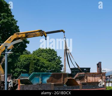 Verladen von Müllcontainern mit einem Kran in einen LKW. Slinger funktioniert. Stockfoto