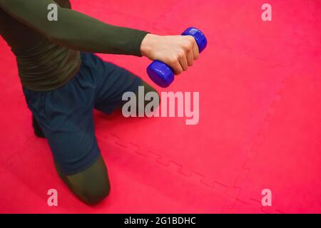 Der Typ in einem thermischen Anzug und Shorts macht Übungen mit Kurzhanteln im Fitnessstudio. Stockfoto