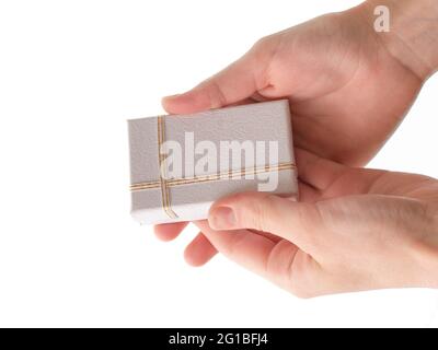 Weibliche Hände halten eine kleine Geschenkbox auf weißem Hintergrund. Stockfoto