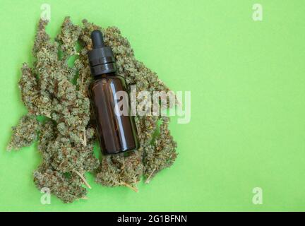 Flasche mit Cannabisöl auf grünem Hintergrund. CBD-THC-Extrakt und medizinischer Cannabisblühungsprozess.Copy space.Flat Lay. Stockfoto