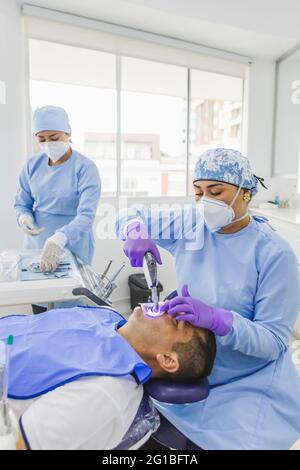 Arzt trägt medizinische Uniform Behandlung des Klienten mit Zahnarztwerkzeug mit Assistent Vorbereitung Instrumente im Krankenhaus Stockfoto