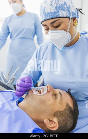 Professionelle ethnische Zahnmediziner tragen medizinische Uniform tun Heilung Verfahren zum Kunden in der Klinik mit Krankenschwester Stockfoto