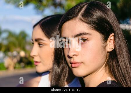 Teenager mit braunen Haaren und Augen in der Nähe von weiblichen Geschwisterchen an sonnigen Tagen auf verschwommenem Hintergrund Stockfoto