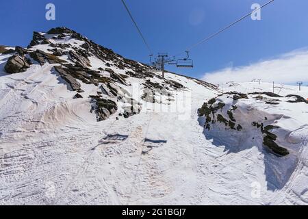 Seilbahn mit Hütten über rauem Bergrücken mit Schnee unter wolkig blauem Himmel in der Provinz Granada Spanien Stockfoto