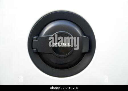 Schwarze Tankklappe mit Schriftzug „FUEL“ auf einem weißen Auto. Nahaufnahme. Stockfoto