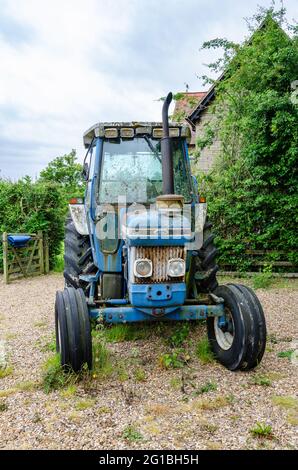 Ein blauer Ford 7610 Traktor, der auf einer Schottereinfahrt geparkt ist. Stockfoto