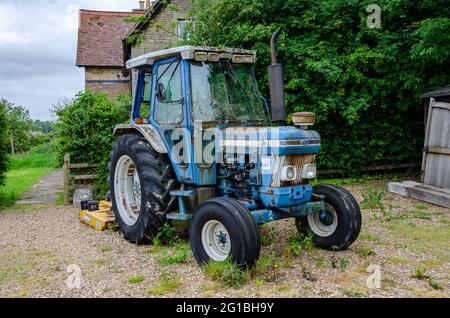 Ein blauer Ford 7610 Traktor, der auf einer Schottereinfahrt geparkt ist. Stockfoto