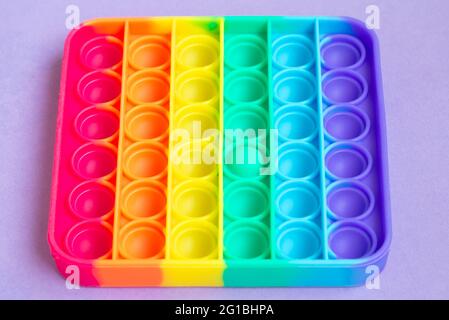 Neues Sinnesspielzeug - Pop it, Antistress-Konzept.Regenbogenfarbe, konkave und konvexe Blasen.Nahaufnahme.Draufsicht. Stockfoto