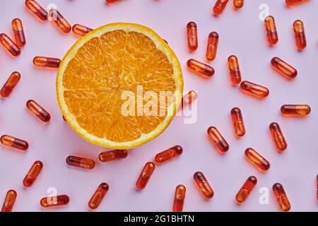 Draufsicht Komposition von reifen geschnittenen Orangen auf rosa Oberfläche in der Nähe verstreut Pillen in Licht Studio angeordnet Stockfoto