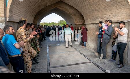 Isfahan, Iran - Mai 2019: Iraner singen und unterhalten sich unter der Khaju Brücke über den Zayandeh Fluss Stockfoto