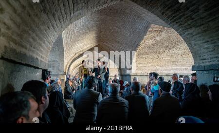 Isfahan, Iran - Mai 2019: Iraner singen und unterhalten sich unter der Khaju Brücke über den Zayandeh Fluss Stockfoto