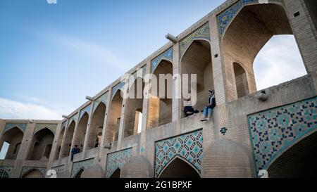 Isfahan, Iran - Mai 2019: Junges iranisches Paar sitzt auf der Khaju-Brücke, die über dem Fluss Zayandeh gebaut wurde Stockfoto