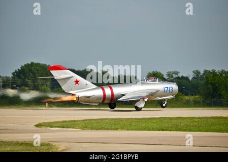 Russische Hochunterschall-Kampfflugzeuge MiG-17, mit Strahltriebwerken, die beim Start auf der Start- und Landebahn des EAA Fly-in (AirVenture), Oshkosh, Wisconsin, aufflammen Stockfoto