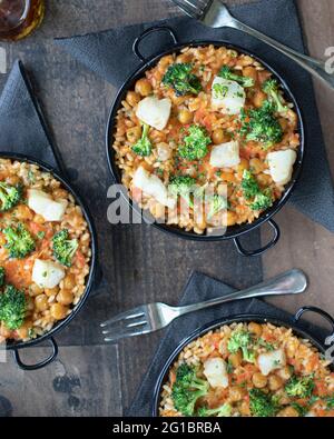 Drei kleine Kabeljau, Kichererbsen und Brokkoli-Paellas. Übersicht, Flat Lay. Partyzeit Stockfoto