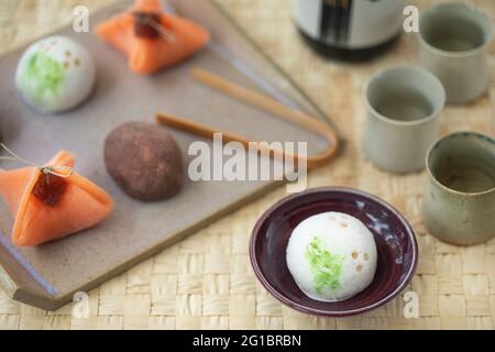 Keramik-Tablett mit kleinen japanischen Süßigkeiten Wagashi, und Sake Keramik kleinen Tassen. Stockfoto