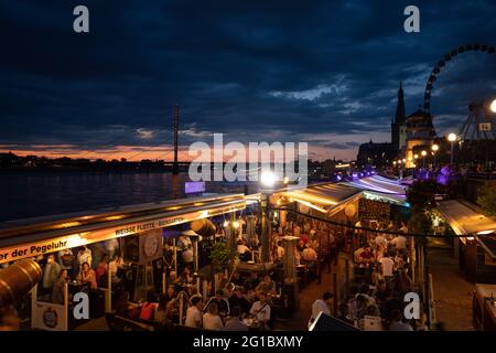 Nachtansicht des wiedereröffnenden Cafés und Restaurants an der Promenade am Rheinufer während der Epidemie COVID-19. Stockfoto
