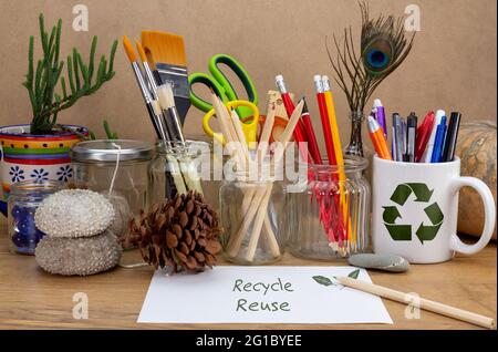 Recycelte Gläser, Zinn und Becher für verschiedene Inhalte auf Holzbank wiederverwendet, wiederverwenden Recycling-Text auf Notizpapier Recycling zu Hause für ein nachhaltiges Leben, s Stockfoto