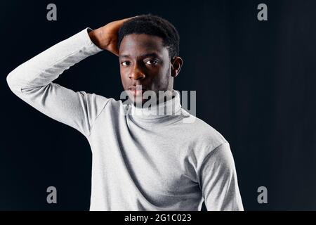 Mann in einem Pullover hält seinen Kopf abgeschnitten Ansicht dunklen Hintergrund Stockfoto