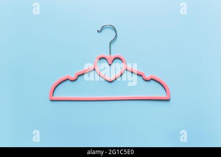 Black Friday oder Kleidung Industrie Konzept auf blauem Hintergrund flach Lay mit einem einzigen rosa Kleiderbügel mit Herzform auf Kleiderbügel Stockfoto