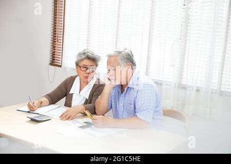 Asiatische ältere Paar ernsthaft besorgt mit der Berechnung Rechnungen zu zahlen pro Monat oder Schulden, Rentner ältere Lesen Darlehen Dokument, Geld Probleme Konzept Stockfoto