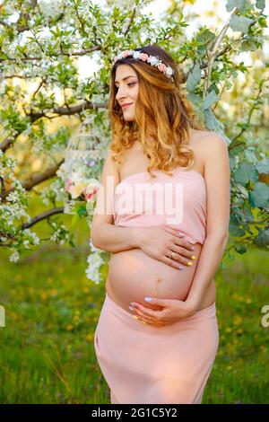 Glückliche, schwanger Frau in rosa Kleid Blick auf Sonnenaufgang.Schwangerschaft. Stockfoto