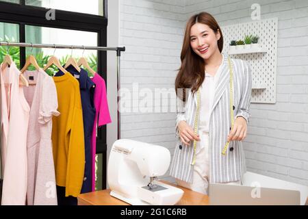 Asiatische schöne junge Modedesignerin Frau mit Nähmaschine im Arbeitszimmer, Schneiderei Konzept Stockfoto