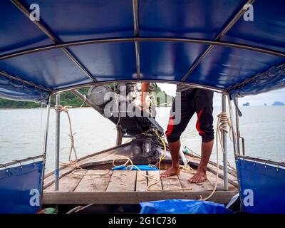 Fischer fahren mit einem lokalen Longtail-Holzboot, steuern das Ruderboot in der Nähe des Motors vorne und fahren zur Insel in Thailand, Blick von innen Stockfoto