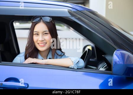 Asiatische Frau, die ein Auto fährt und glücklich lächelt, mit freudem positiven Ausdruck während der Fahrt zur Reise, genießen die Menschen lachen Transport und fahren Stockfoto