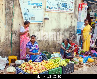 Indische Markthändlerinnen, die Äpfel, Bananen, Orangen und Gemüse vom Straßenstand in Chaudi (Canacona), Goa, Indien, verkaufen Stockfoto