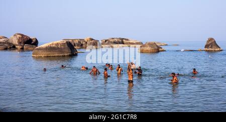 Gruppe von indischen Männern, die in der Nähe der schönen Felsformation baden, Agonda Beach, Goa, Indien Stockfoto