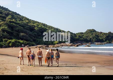 Eine Gruppe von ausländischen Touristen mittleren Alters, die an einem idyllischen, einsamen Strand entlang gehen, Agonda, Goa, Indien Stockfoto