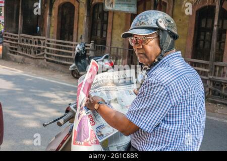 Älterer indischer Herr saß auf dem Roller und las die Zeitung „The Times of India“, Margao, Goa, Indien Stockfoto