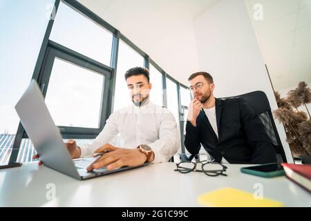 Zwei gutaussehende männliche Büroangestellte am Laptop Stockfoto