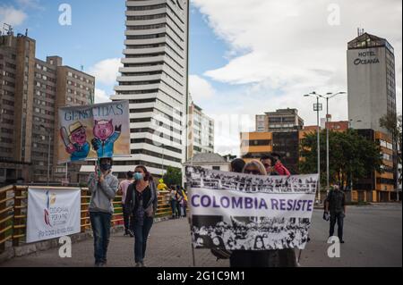 Bogota, Kolumbien. Juni 2021. Die Demonstranten halten ein Schild mit Karikaturen, auf denen „Völkermorde“ als ein weiterer golder dargestellt werden, der „Colombia resists“ liest, während sich Menschen und indigene Misak-Gemeinschaften versammeln, um inmitten von Polizeibrutalität und Unruhen während regierungsfeindlicher Proteste auf die Ankunft der Interamerikanischen Menschenrechtskommission (CIDH) zu warten 70 Tote im vergangenen Monat der Demonstrationen, am 6. Juni 2021 in Bogota, Kolumbien. Kredit: Long Visual Press/Alamy Live Nachrichten Stockfoto