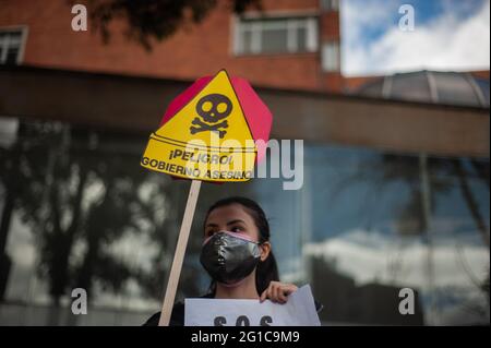 Bogota, Kolumbien. Juni 2021. Ein Demonstrator hält ein Schild mit der Aufschrift „Warnung! Die Regierung ist ein Mörder“, während sich Menschen und indigene Misak-Gemeinschaften versammeln, um angesichts der Brutalität der Polizei und der Unruhen während regierungsfeindlicher Proteste, die im vergangenen Monat bei Demonstrationen in Bogota, Kolumbien, am 6. Juni, mindestens 70 Tote erreichen, auf die Ankunft der Interamerikanischen Menschenrechtskommission (CIDH) zu warten. 2021. Kredit: Long Visual Press/Alamy Live Nachrichten Stockfoto