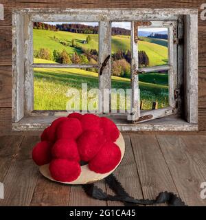 Blick durch ein Fenster mit Bollenhut auf Holztisch Stockfoto