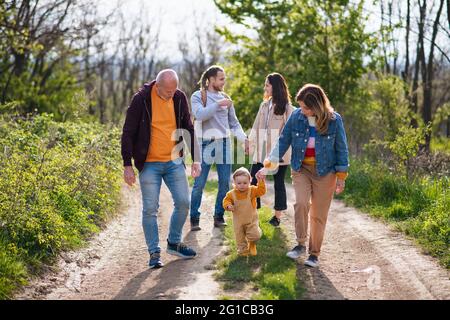 Kleines Kleinkind mit Eltern und Großeltern auf einem Spaziergang im Freien in der Natur. Stockfoto