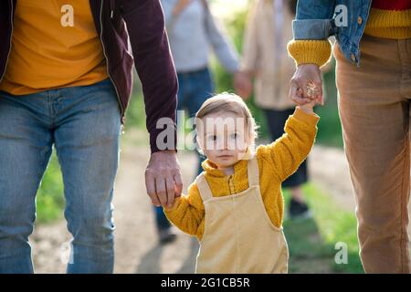 Kleines Kleinkind mit unverkennbaren Eltern und Großeltern auf einem Spaziergang im Freien in der Natur. Stockfoto