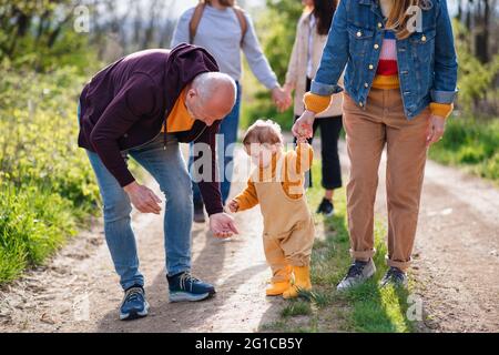 Kleines Kleinkind mit unverkennbaren Eltern und Großeltern auf einem Spaziergang im Freien in der Natur. Stockfoto