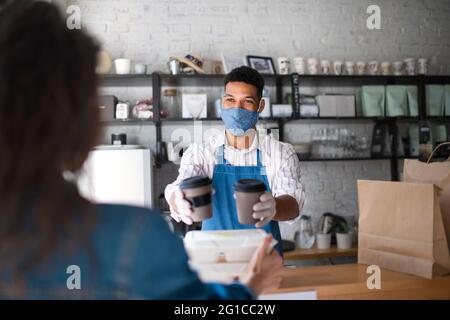 Der Kellner gab den Gästen im Coffee Shop verpacktes Essen zum Mitnehmen und Kaffee, Coronavirus-Konzept. Stockfoto