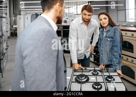 Männliche Verkäuferin hilft jungen Paaren, ein neues Zuhause zu wählen Gerät Stockfoto