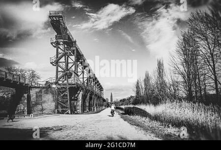 Stahlrahmenbrücke an der Emscher Promenade mitten im Landschaftspark Duisburg Nord. Industriemaschinen und verrostete Komponenten. Ironworks blas Stockfoto