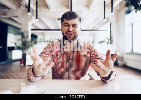 Fröhlicher junger Geschäftsmann, der am Schreibtisch sitzt und die Kamera anschaut Stockfoto