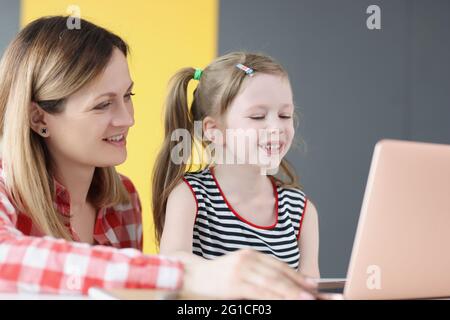 Junge lächelnde Frau führt Kurse mit Kind auf dem Laptop durch Stockfoto